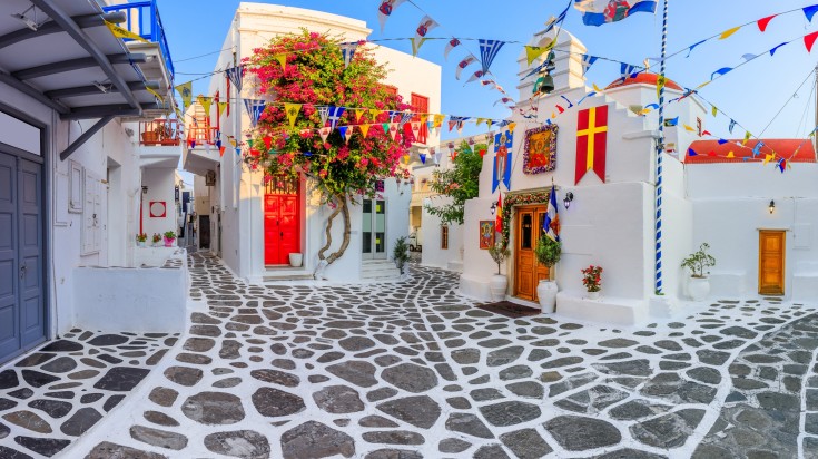 Narrow streets in Mykonos with flags.