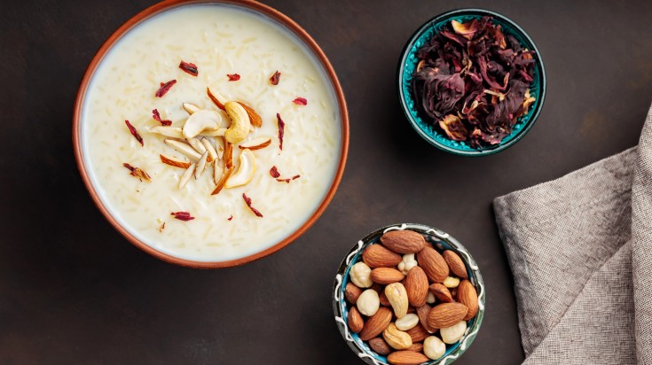 A bowl of kheer presented with garnishes on the side.