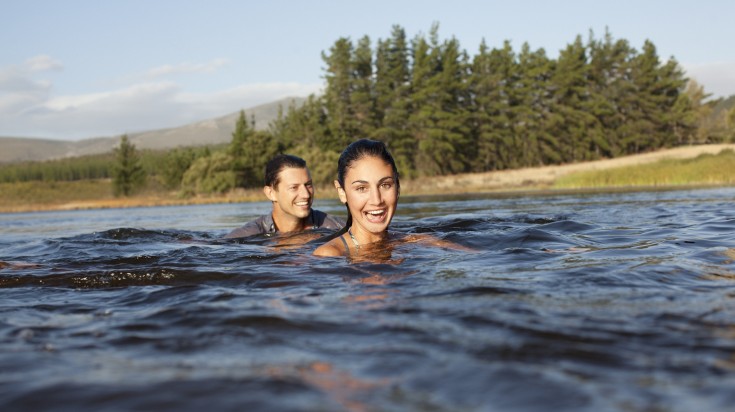 A couple swimming in a lake on a hot summer day.