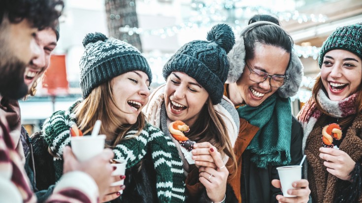 A jolly group of tourists enjoying treats in a Christmas market.