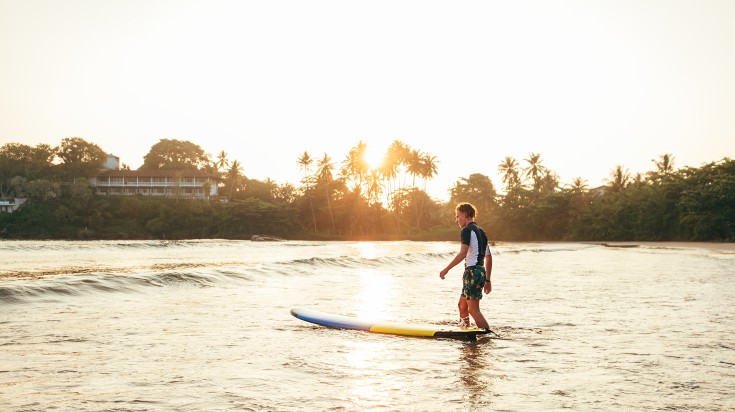A man surfing in Dewata Beach, Sri Lanka.