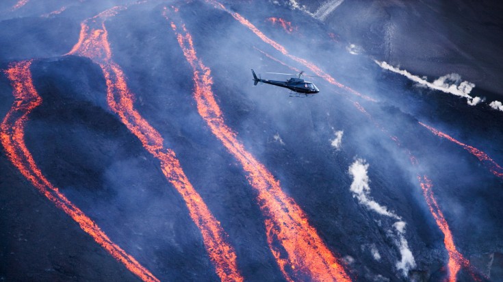 A tour helicopter flying over lavafalls at Fimvorduhals.