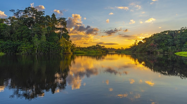 Reflection of a sunset by a lagoon inside the Amazon Rainforest in Peru.