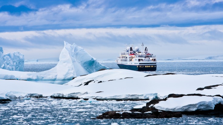 A cruise ship passing by icebergs in Antarctica. 