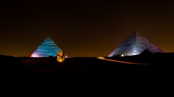A car passing at night between the pyramids of the Giza in Cairo, Egypt