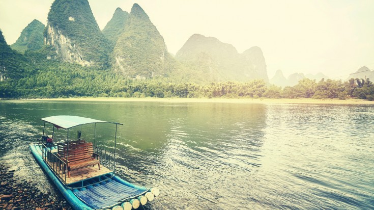 Raft made of bamboo floating on a river surrounded by hills