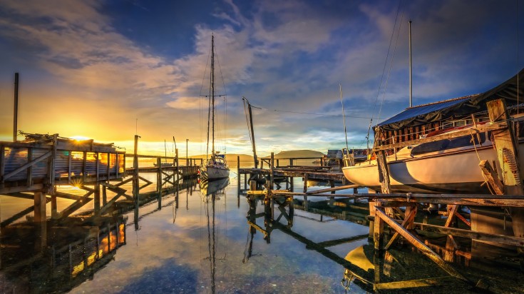 Boats parked at a port in Dunedin during sunrise.