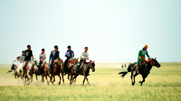 People horse racing in grassland in China.