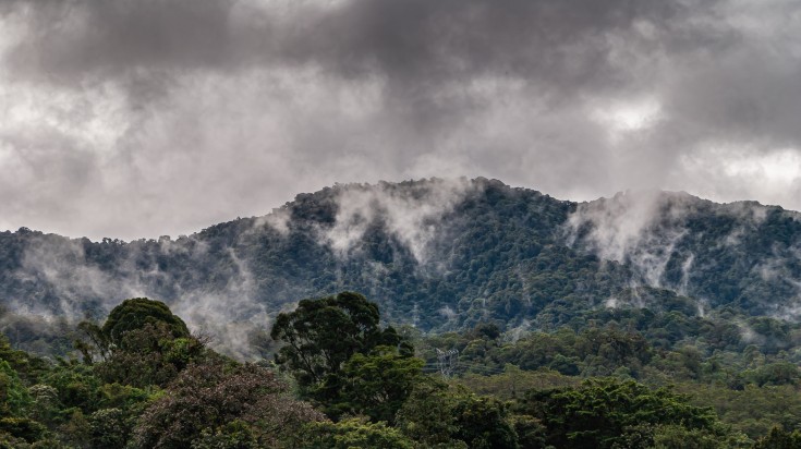 Tree covered mountain range under heavy rainy cloudscape in Costa Rica.