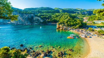 A beach at Corfu on a summer day in Greece with a lot of greenery.