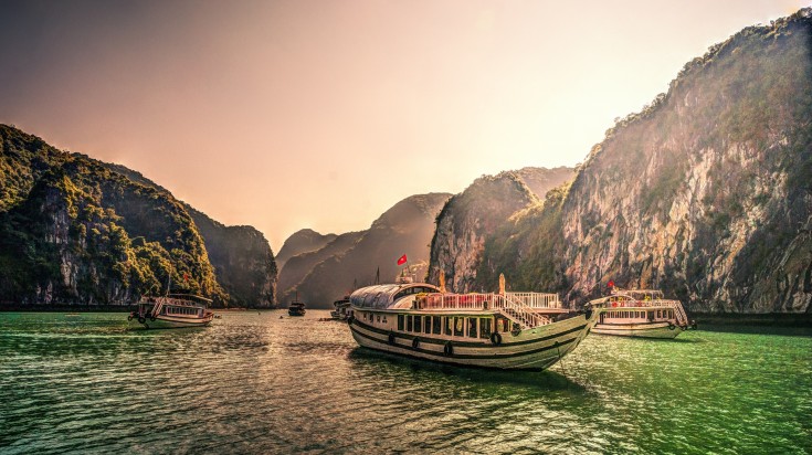 Cruise ship in the green rocks in sunset light on Halong Bay.