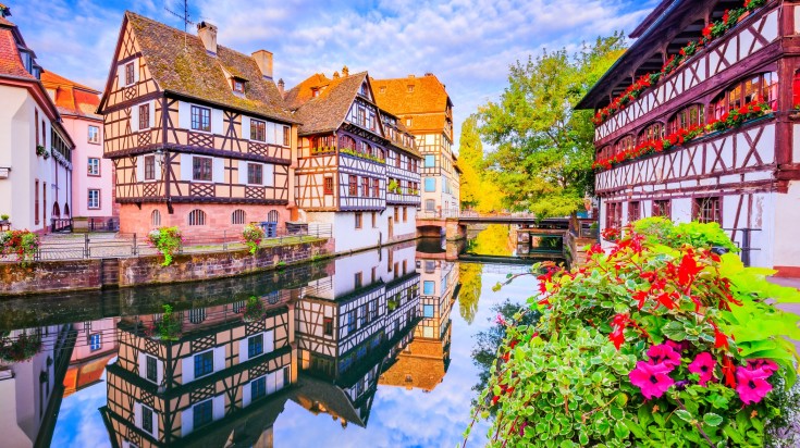 Traditional half timbered houses of Petite France reflected on a lake.