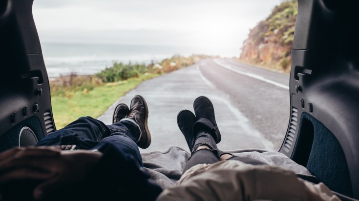 A couple laying in the car trunk, enjoying the view the road trip has to offer