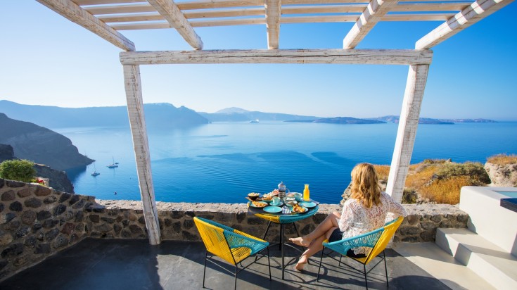 Woman enjoying breakfast with beautiful view over Santorini