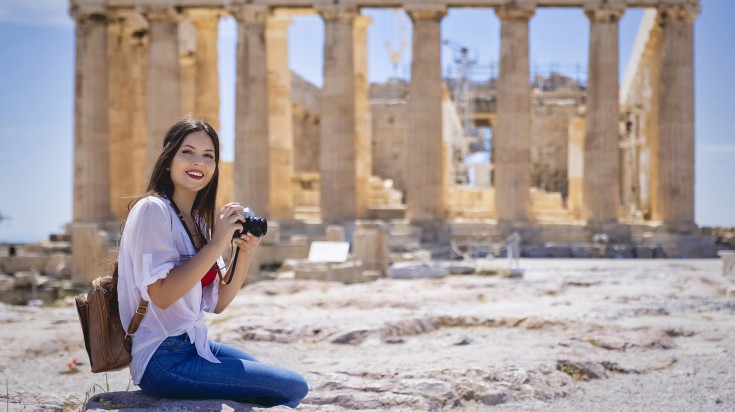 A woman taking pictures of the Parthenon Temple at the Acropolis of Athens