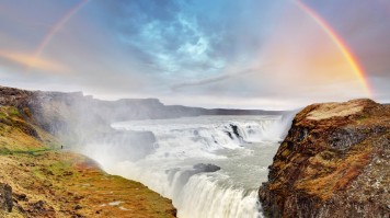 The Gullfoss waterfall with a bright rainbow in the distance in Iceland. 