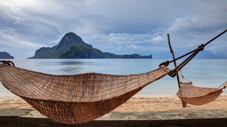 Hammocks anchored between palm trees on El Nido, Palawan island.