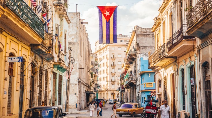 A street in Havana with the Cuban flag and few people.