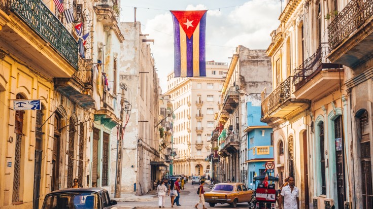 A street in Havana with the Cuban flag and few people.