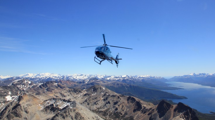 A helicopter flying above the beautiful mountains in Ushuaia.