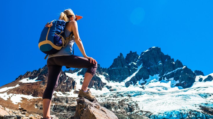 Women hiker stands on the rock and enjoys the view in Chile.