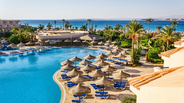 An empty swimming pool with beach benches and trees all around in Egypt. 