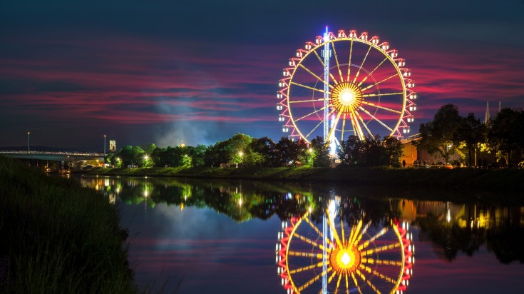 You can see ferris wheel at night entirely lit up in Hungary in June. You can see ferris wheel at night entirely lit up in Hungary in June.