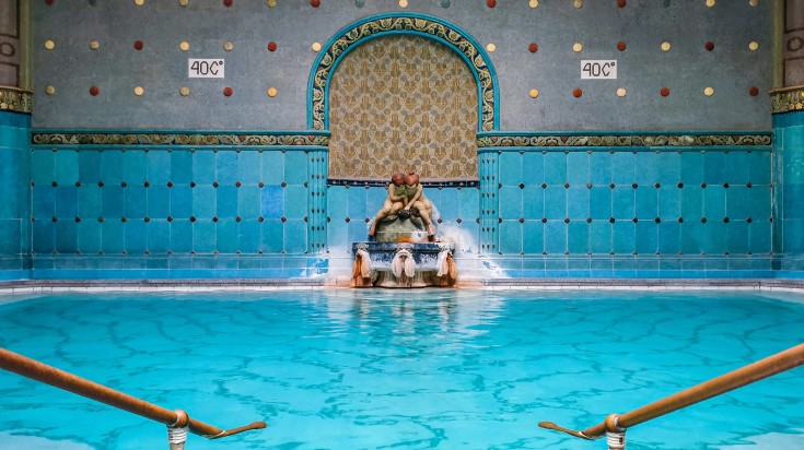 A spa in Hungary with blue tiles and fountain in the middle.