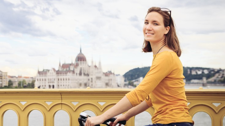 A woman cycling in Budapest on a clear day in Hungary in March.