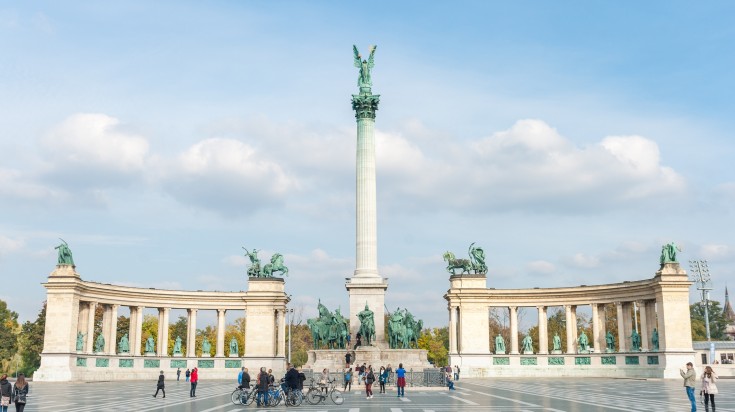 Heroes Square in Budapest with people walking and cycling around.