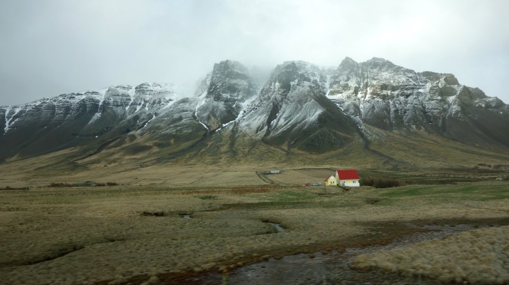 Icelandic idyllic landscape with a house and majestic snowy mountain.