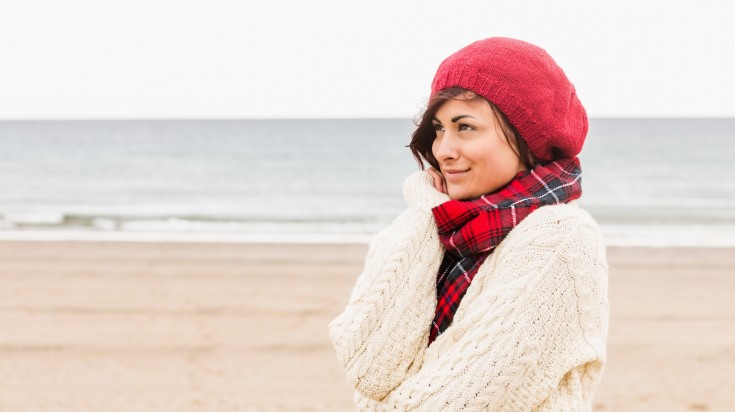 Side view of woman in warm clothing looking away on the beach