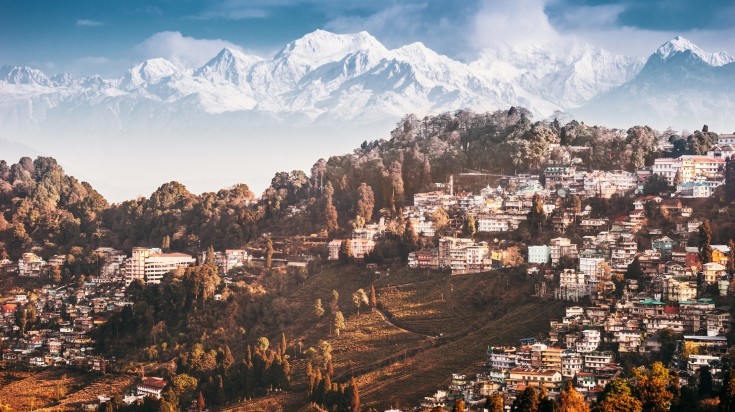 A hill station with snowy mountains behind it