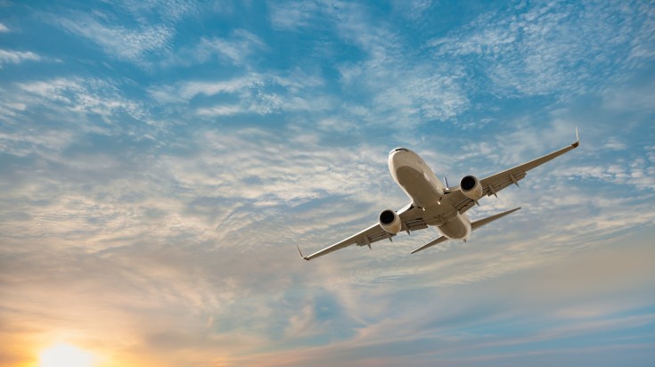 A plane flying in a cloudy blue sky.