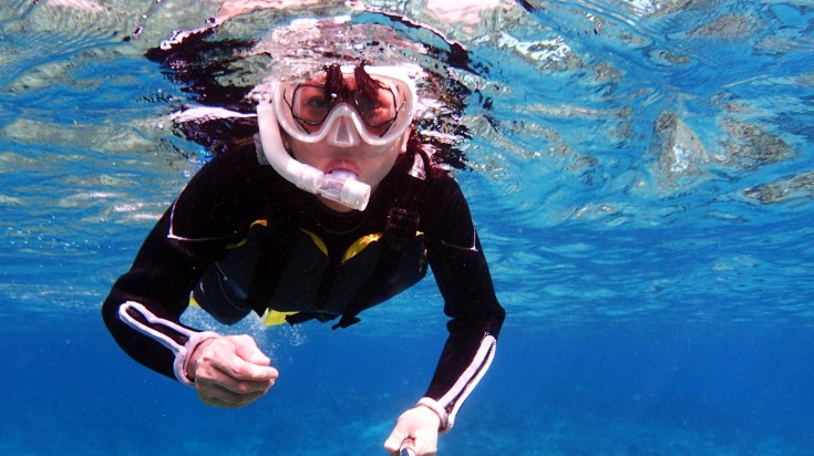 A tourist girl snorkeling in tropical water in Japan during summer.