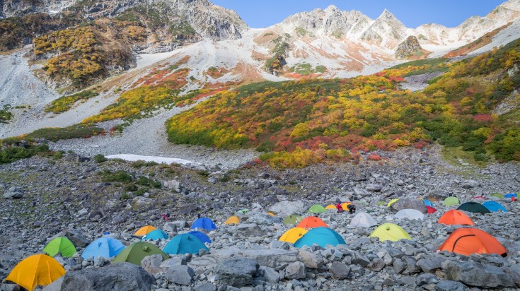 Colorful tents with hills all round in the Kamikochi-Yari-Hotaka Circuit in Japan. 