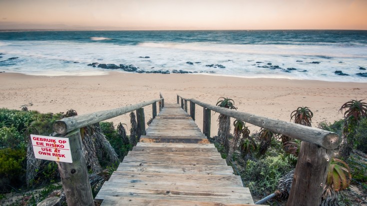 Rough sea and golden sand at the rugged coast in Jeffreys bay, South Africa