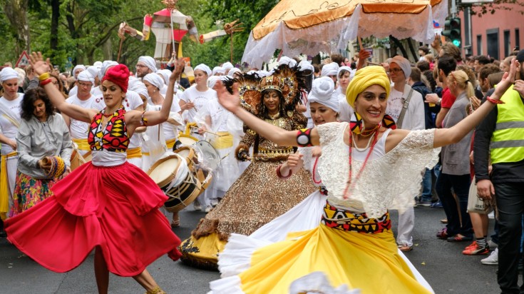 People dance in colorful costumes during Karneval Der Kulturen.