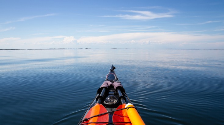 A cockpit view of a sea kayakar crossing the sea in Sweden in August.