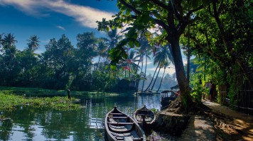 A scenic view of boats under a blue sky in backwaters in Allepey town.