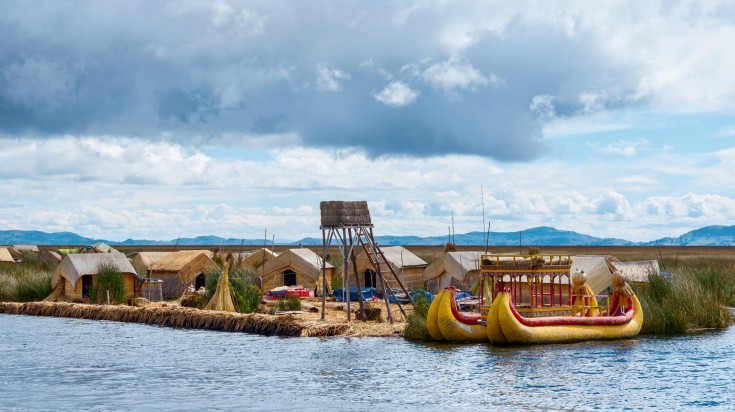 A view of Lake Titicaca with boat and huts.