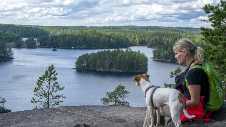 A hiker woman and dog admiring the beauty of Lemmenjoki National Park. A hiker woman and dog admiring the beauty of Lemmenjoki National Park.
