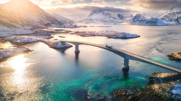 Aerial view of bridge over the sea and snowy mountains in Lofoten Islands.