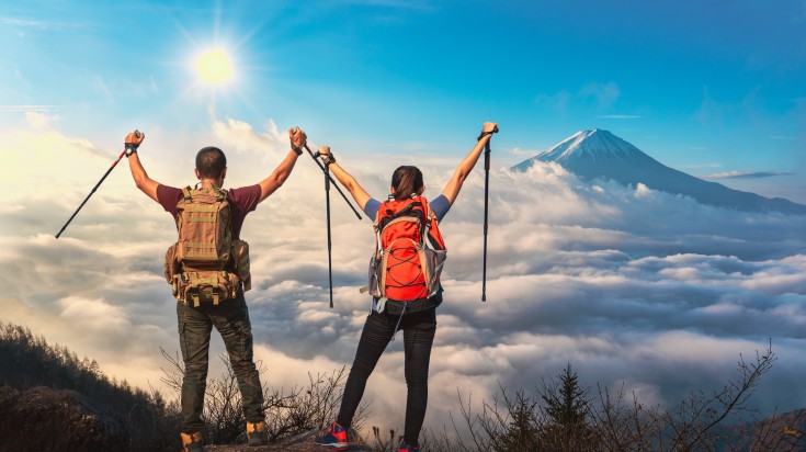 Young couple climbing up on the peak of mountain near Mount Fuji.