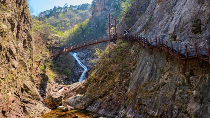 Footbridge on hiking trail with hikers tourists at Biryong Falls Waterfall.