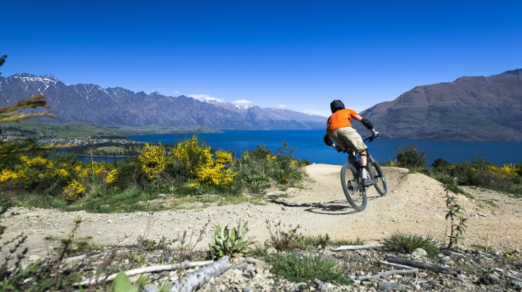 A man biking in Queenstown on a sunny day.