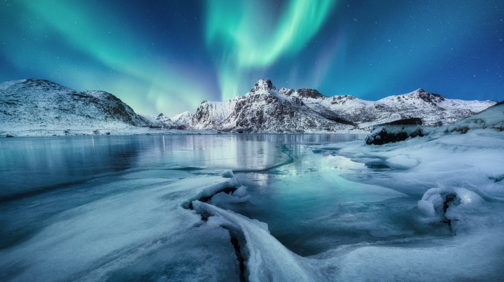 Aurora Borealis, Lofoten islands, Norway. Mountains and frozen ocean. Winte