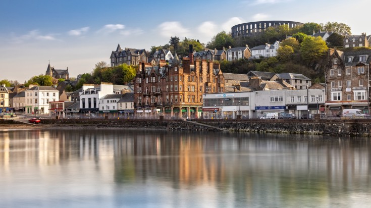 A scenic view of Oban with the water reflecting the buildings.