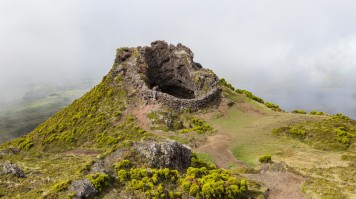 A woman looks down the mouth of a dormant volcano