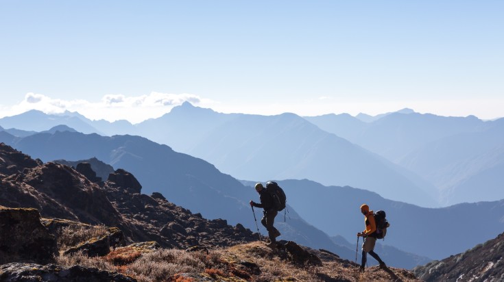 Two men climbing the rocky slopes in Nepal with their backpacks.